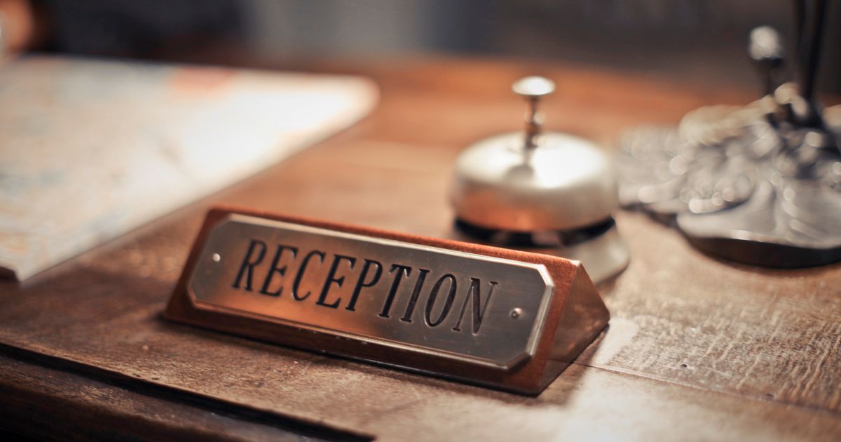 A hotel reception desk with a reception sign and service bell