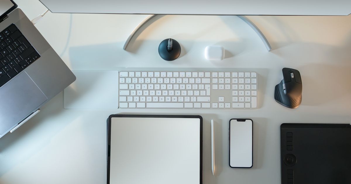 A flat-lay of a laptop, monitor, keyboard, phone and tablet on a desk